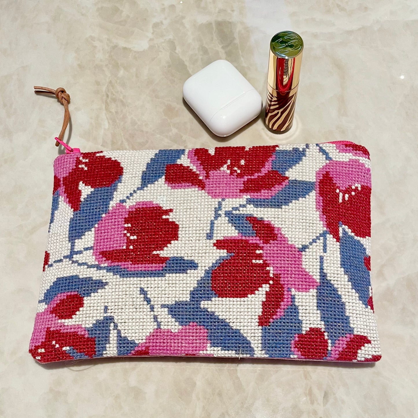 Ferdig magnolia clutch med nydelig magnolia mønster, lebestift og airpods
