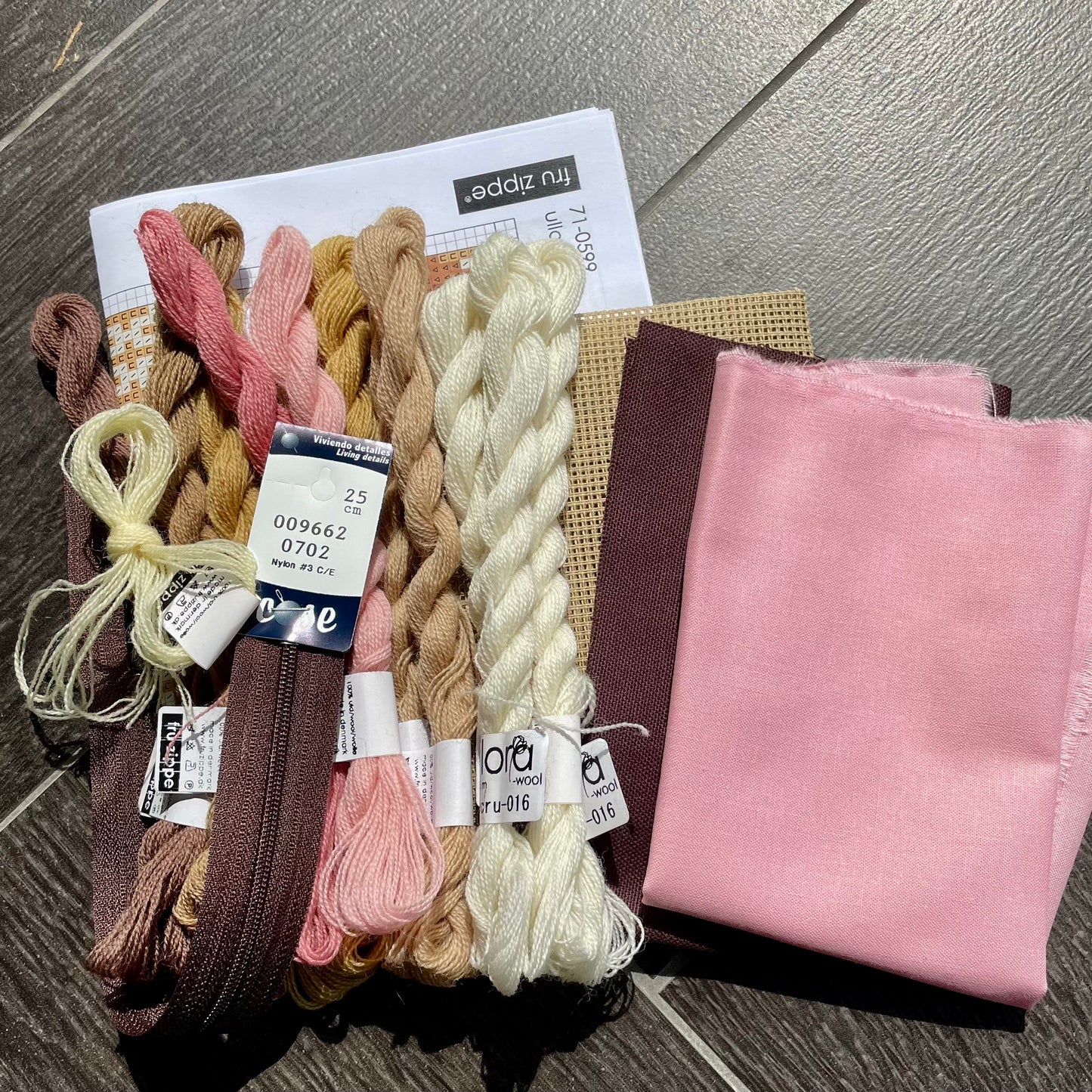 Innhold i Ulla broderikit; stramei, ullgarn, glidelås, bakstykke og for