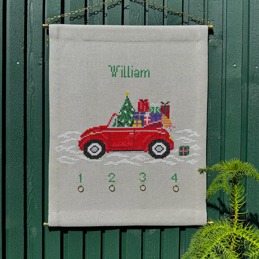 Gavebil adventskalender hengt opp på grønn vegg