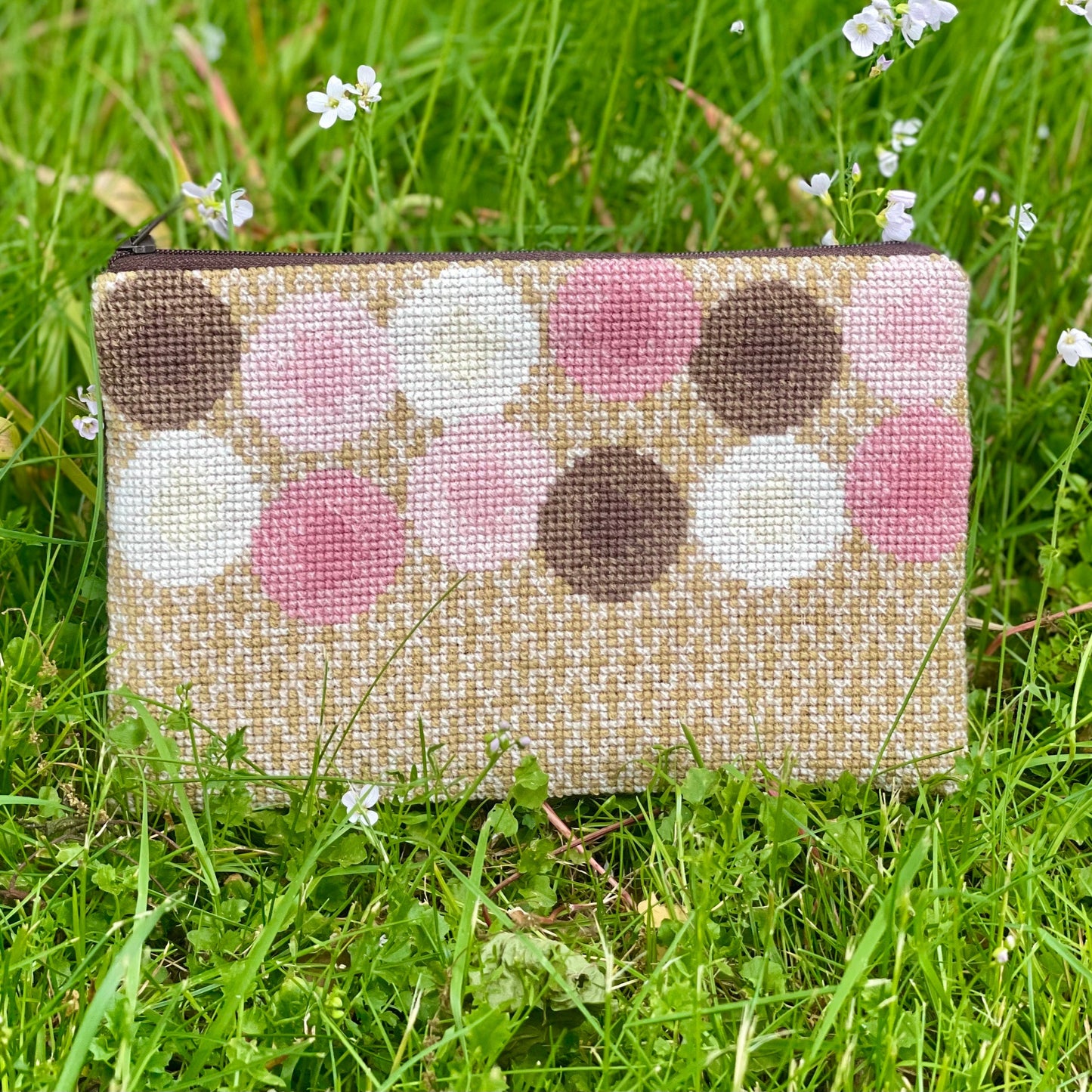 Ferdig Ulla clutch plassert på gresset. Clutchen er i gull med rosa, brune og hvite sirkler