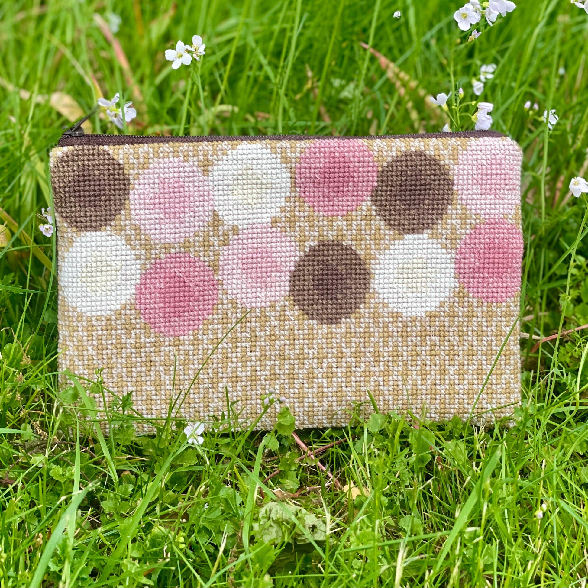Ferdig Ulla clutch plassert på gresset. Clutchen er i gull med rosa, brune og hvite sirkler