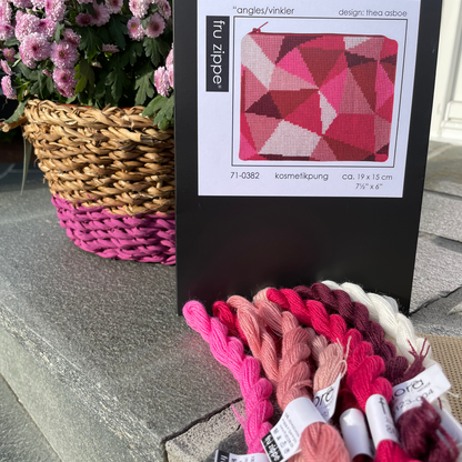 Angles med garn og eske. Rosa blomst i bakgrunnen
