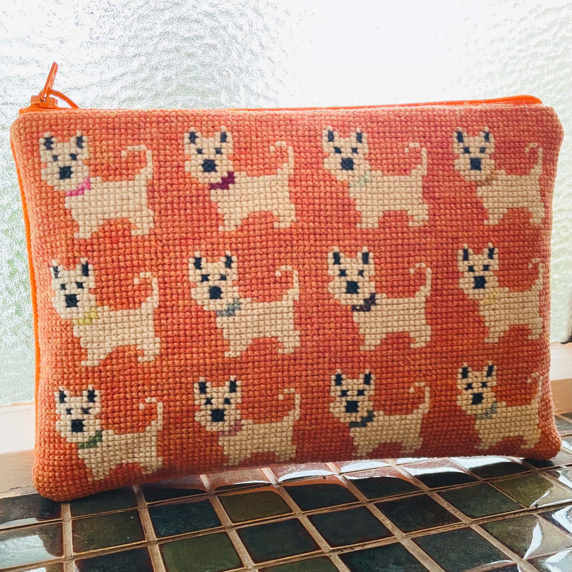 Ferdig coco clutch med et sjarmerende motiv med hunder på oransje bakgrunn.