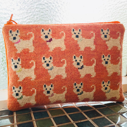Ferdig coco clutch med et sjarmerende motiv med hunder på oransje bakgrunn.