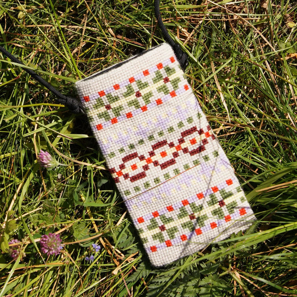 Kunna mobilveske ferdig broderi liggende på gresset
