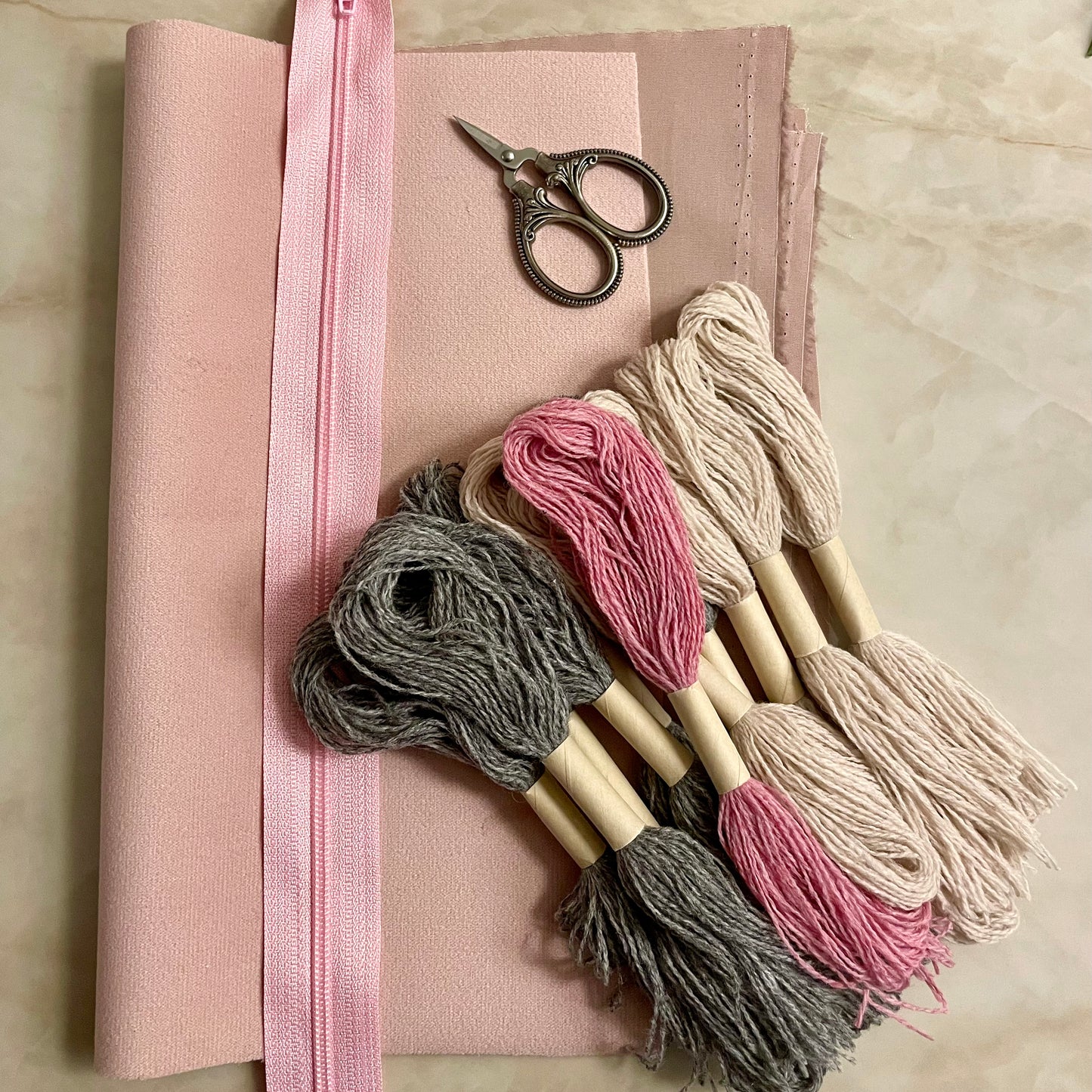 Innhold i Lucca clutch broderikit, garn, glidelås, bakstykke og for