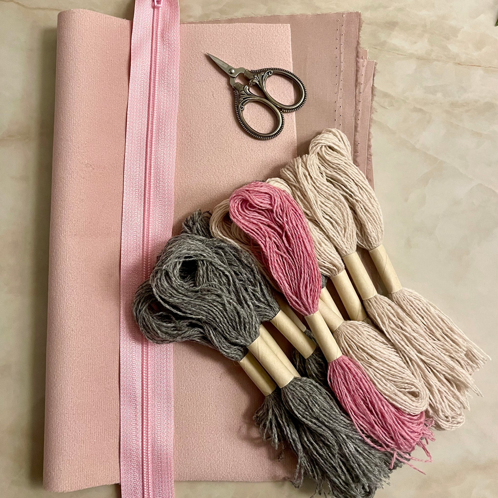 Innhold i Lucca clutch broderikit, garn, glidelås, bakstykke og for