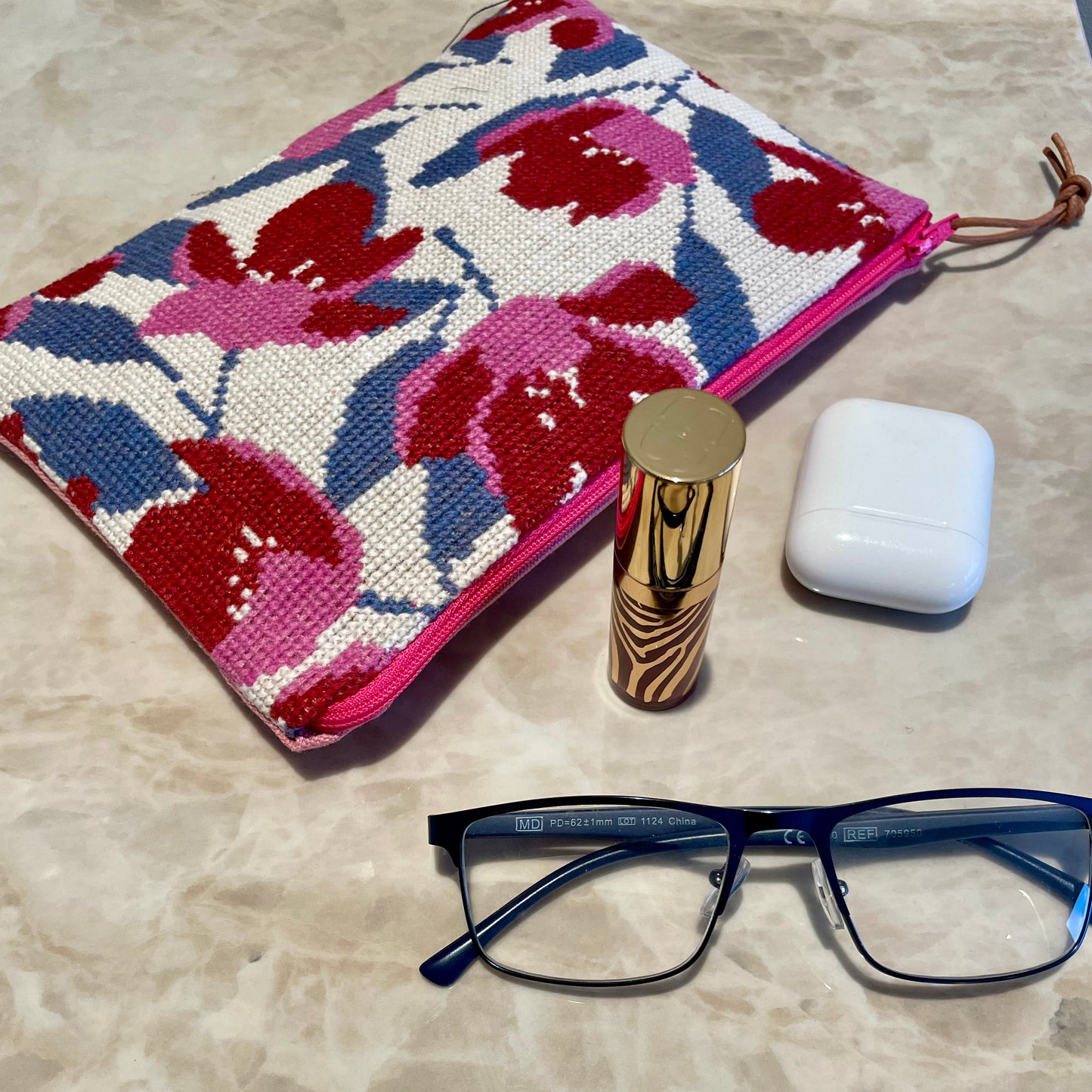 Ferdig magnolia clutch med nydelig magnolia mønster, lebestift, briller og airpods