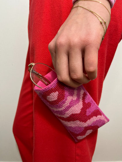 Rosa waves brilleetui under bruk holdes i hånd av kvinne med rød kjole